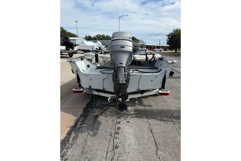 Slide: The Image of 1998 Alumacraft boat with outboard motor on a trailer, parked on a street. - 5