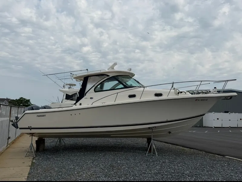 The Image of A 2014 Pursuit OS 315 Offshore boat is on a gravel lot. It features a sleek design. - 0
