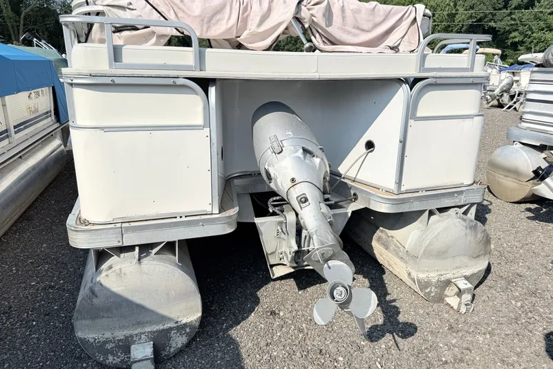 Slide: The Image of 1999 Crest 240 pontoon boat with outboard motor, parked on gravel surface. - 3