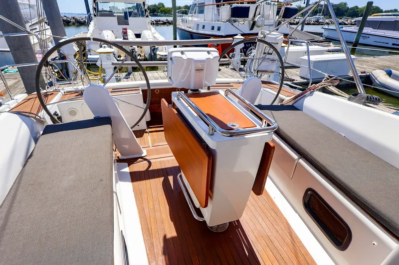 Slide: The Image of 2016 Hanse 385 yacht cockpit with dual steering wheels and wooden flooring at a marina. - 61