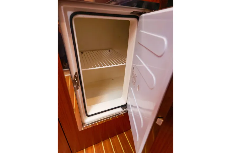 Slide: The Image of Open refrigerator inside 2016 Hanse 385 yacht, showcasing interior shelving and wooden cabinetry. - 28