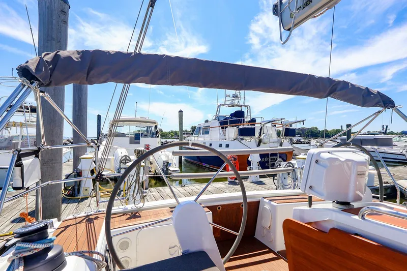 Slide: The Image of 2016 Hanse 385 sailboat cockpit view at marina, featuring steering wheel and docked boats. - 63