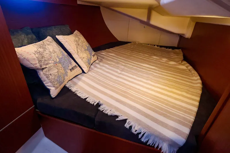 Slide: The Image of Cozy cabin bed in 2016 Hanse 385 yacht with striped blanket and map-themed pillows. - 49