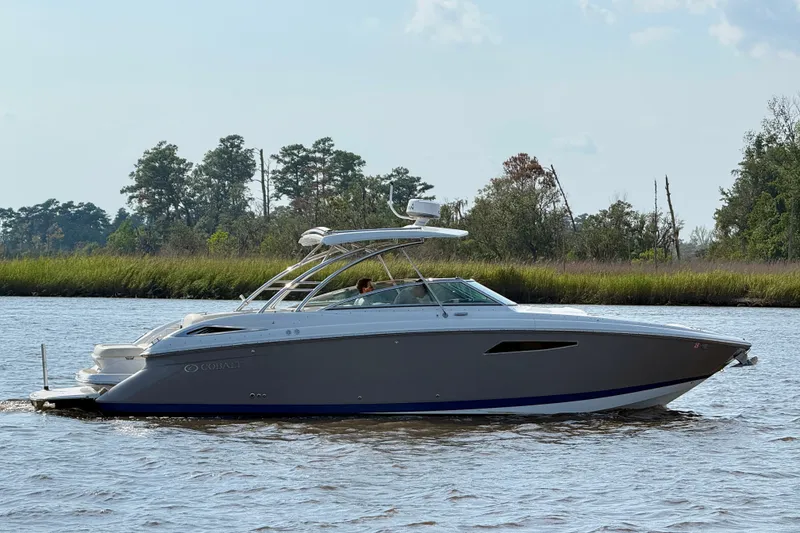 Slide: The Image of 2018 Cobalt R35 boat cruising on a scenic river with lush greenery. - 9