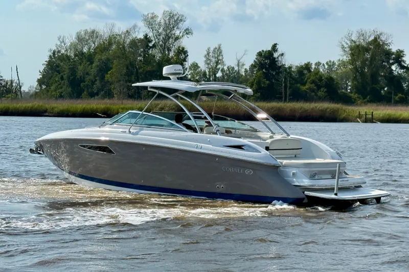 Slide: The Image of 2018 Cobalt R35 boat cruising on a river with lush greenery in the background. - 31