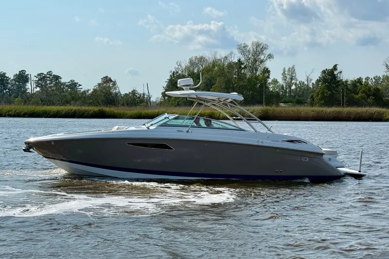 Slide: The Image of 2018 Cobalt R35 boat cruising on a calm river with lush greenery. - 10