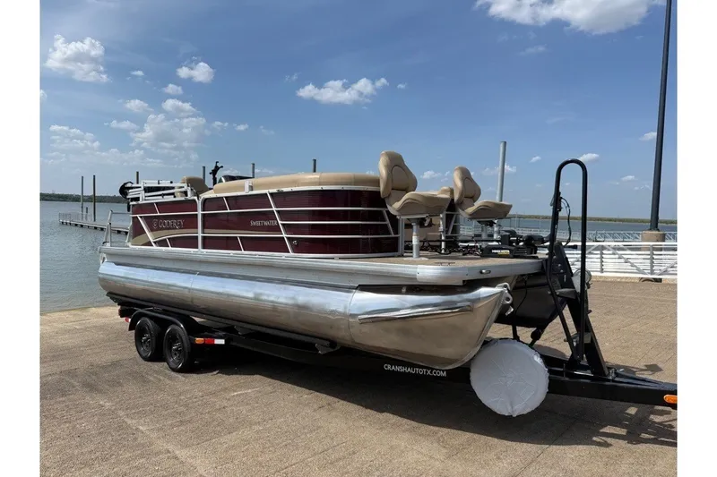 Slide: The Image of 2021 Godfrey Sweetwater 2286 FS pontoon boat on trailer by a lake under blue sky. - 11