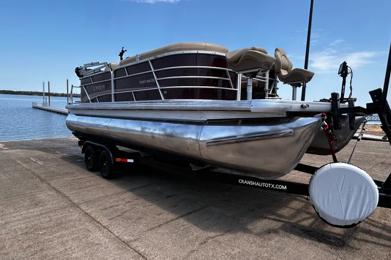 Slide: The Image of 2021 Godfrey Sweetwater 2286 FS pontoon boat on trailer by a lake. - 69