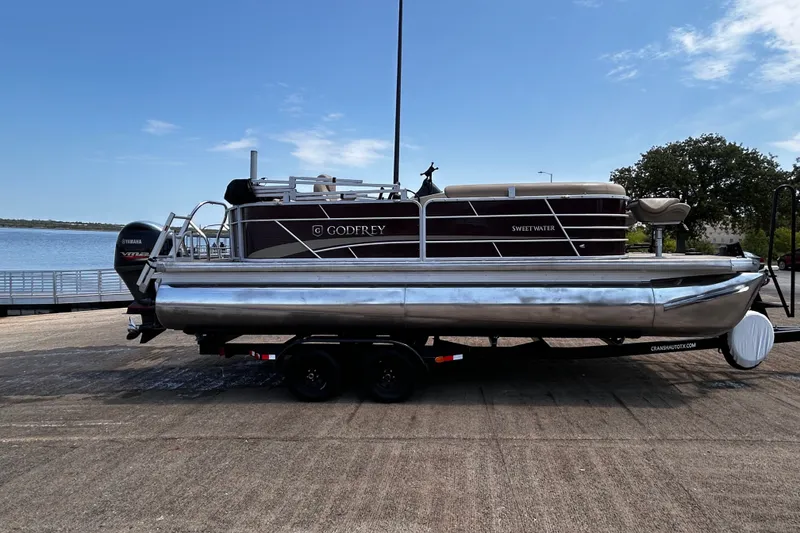 Slide: The Image of 2021 Godfrey Sweetwater 2286 FS pontoon boat on trailer by a lake. - 73