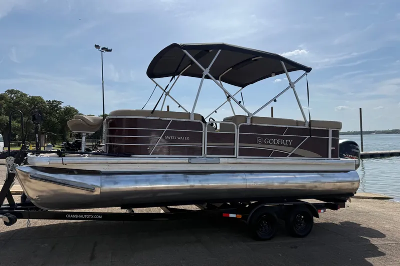 Slide: The Image of 2021 Godfrey Sweetwater 2286 FS pontoon boat on trailer by a lake. - 48