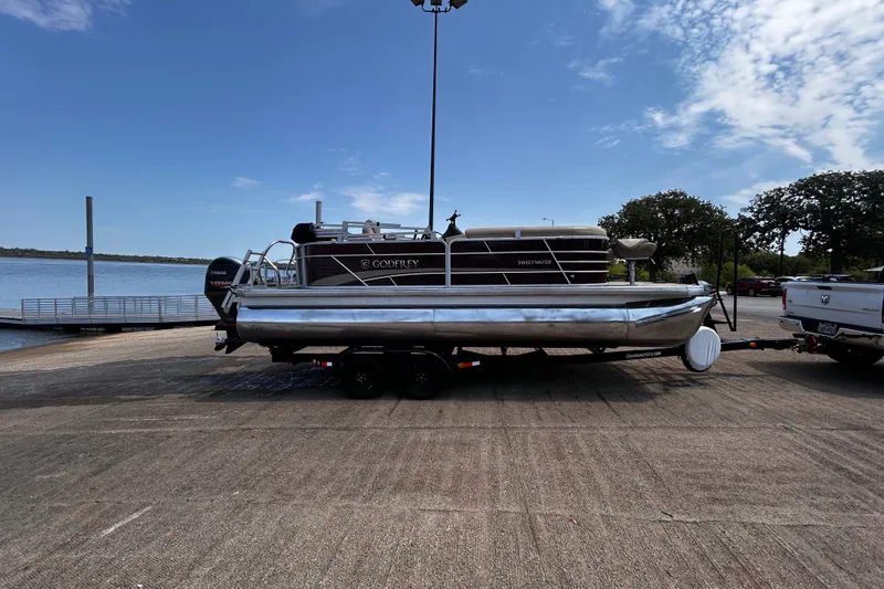 Slide: The Image of 2021 Godfrey Sweetwater 2286 FS pontoon boat on trailer by a lakeside dock. - 72