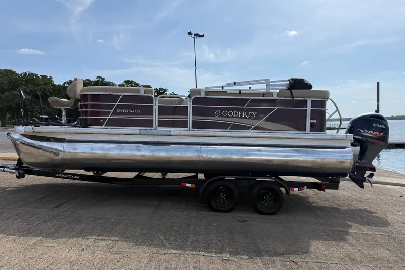 Slide: The Image of 2021 Godfrey Sweetwater 2286 FS pontoon boat on trailer, parked near a lake. - 22