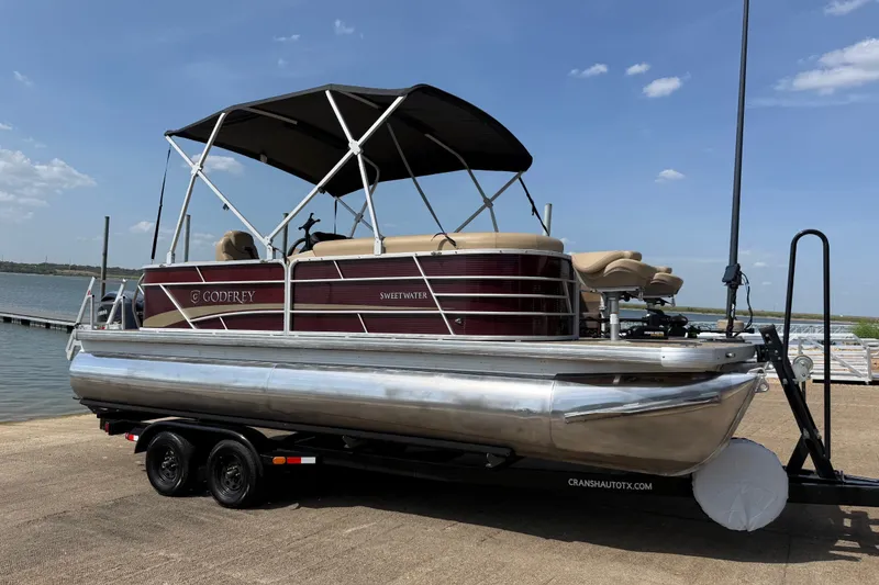 Slide: The Image of 2021 Godfrey Sweetwater 2286 FS pontoon boat on trailer by a lake. - 1