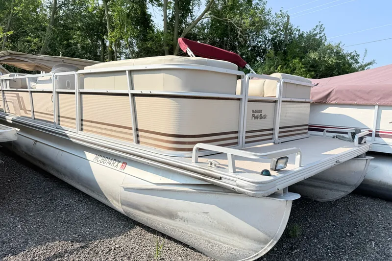 The Image of 1998 Harris FloteBote 220 Classic pontoon boat parked on gravel, surrounded by trees. - 1