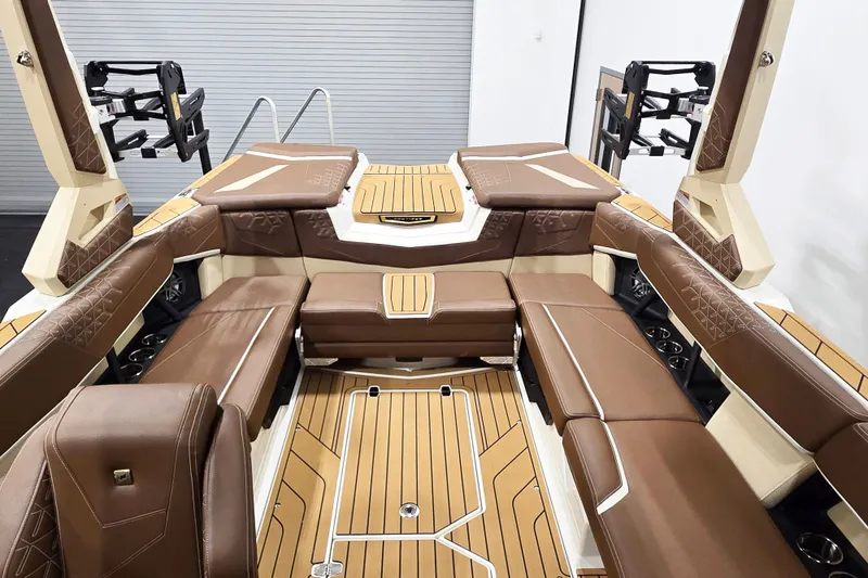 Slide: The Image of The image shows the luxurious interior of a Nautique Super Air Nautique S23 boat with brown leather seating and wood flooring. - 12