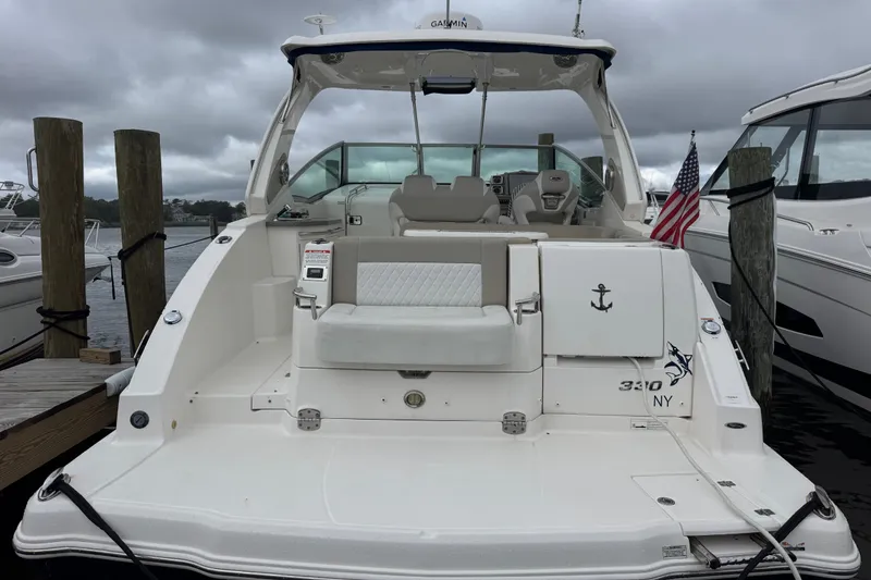Slide: The Image of 2013 Chaparral 330 Signature boat docked, featuring a spacious deck and American flag. - 1