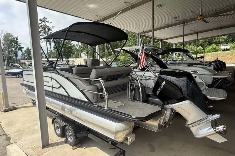 Slide: The Image of 2021 Barletta L25U pontoon boat with Mercury engine, parked under a canopy. - 4