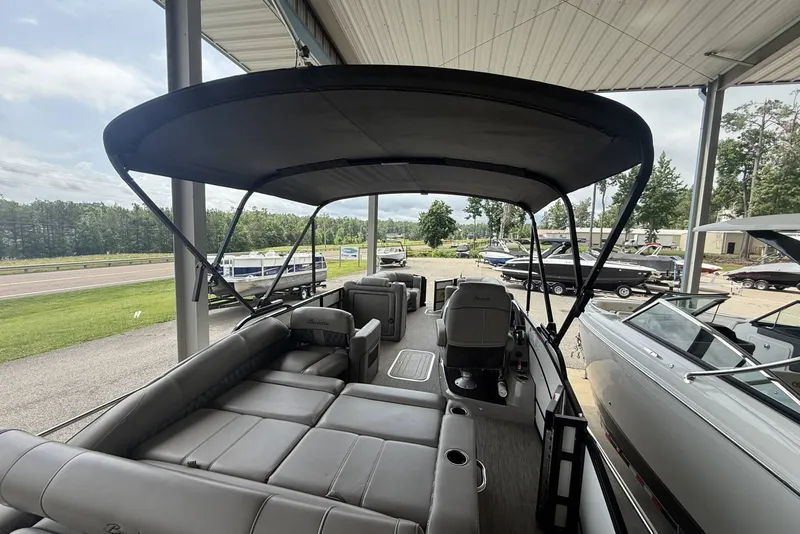Slide: The Image of 2021 Barletta L25U pontoon boat with canopy, parked in a marina setting. - 14