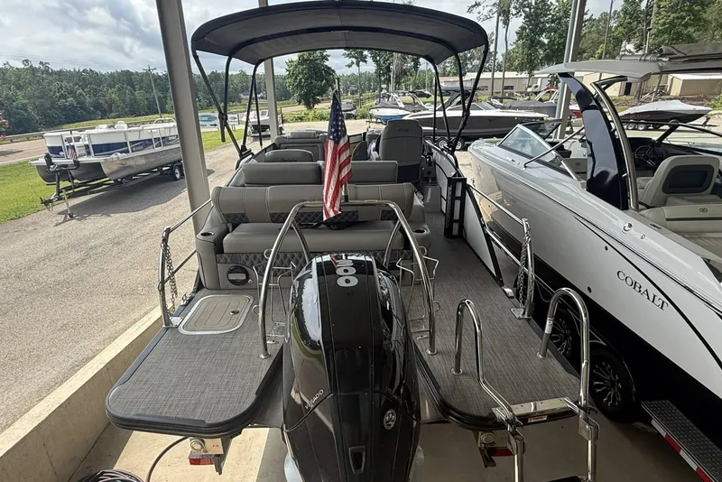 Slide: The Image of 2021 Barletta L25U pontoon boat with American flag, docked alongside other boats. - 5