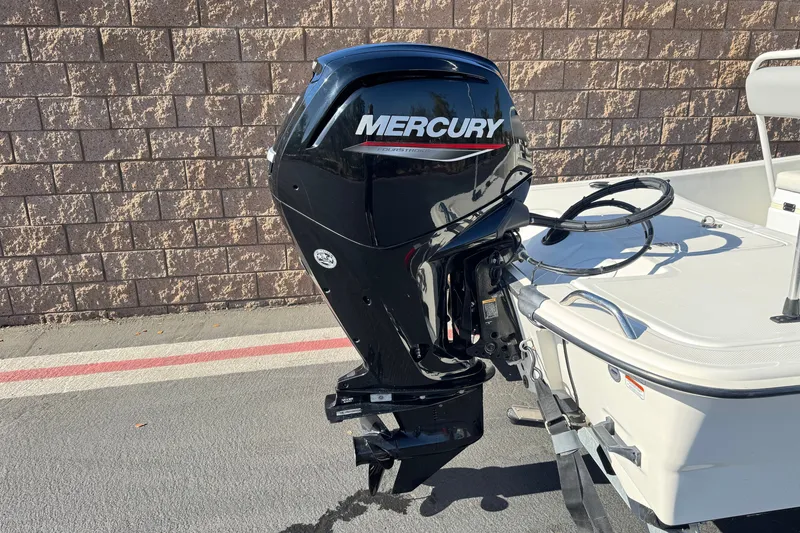 Slide: The Image of 2023 Mako Pro Skiff 17 CC with Mercury outboard motor, parked by a brick wall. - 6