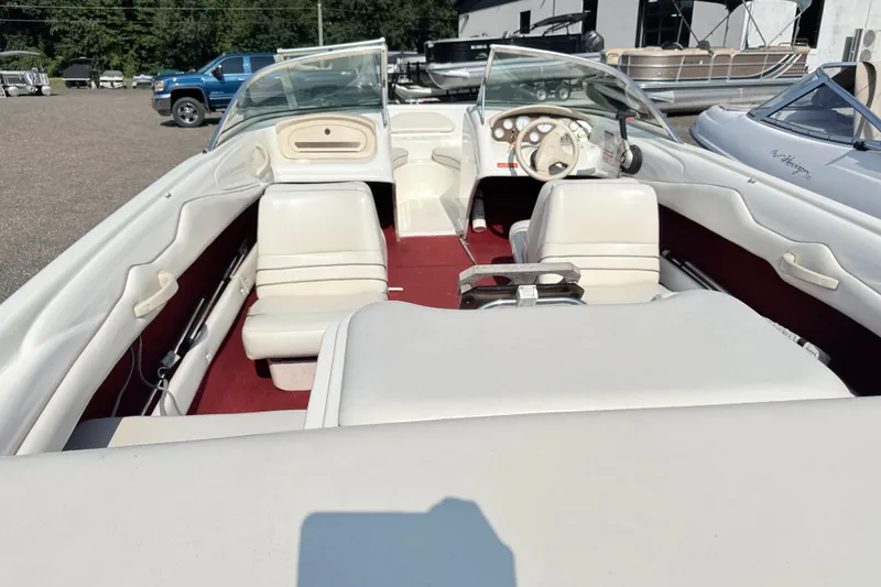 Slide: The Image of 1995 Searay 195 boat interior with white seats and red carpet, parked outdoors. - 9