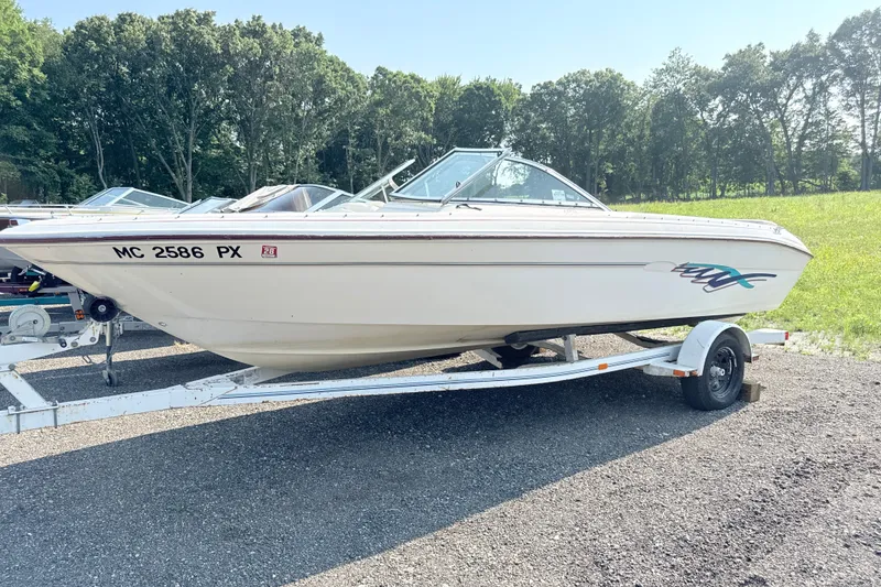 The Image of 1995 Searay 195 boat on trailer, parked outdoors with trees in background. - 0