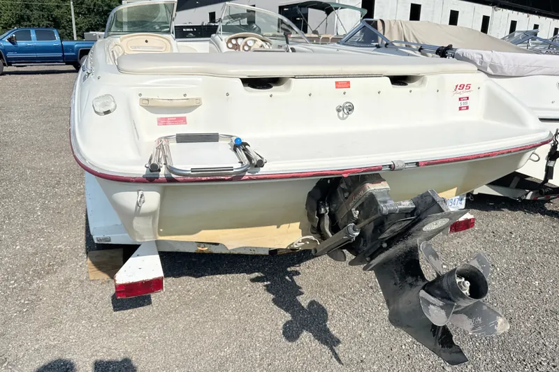 Slide: The Image of 1995 Searay 195 boat rear view with outboard motor in a parking lot. - 1