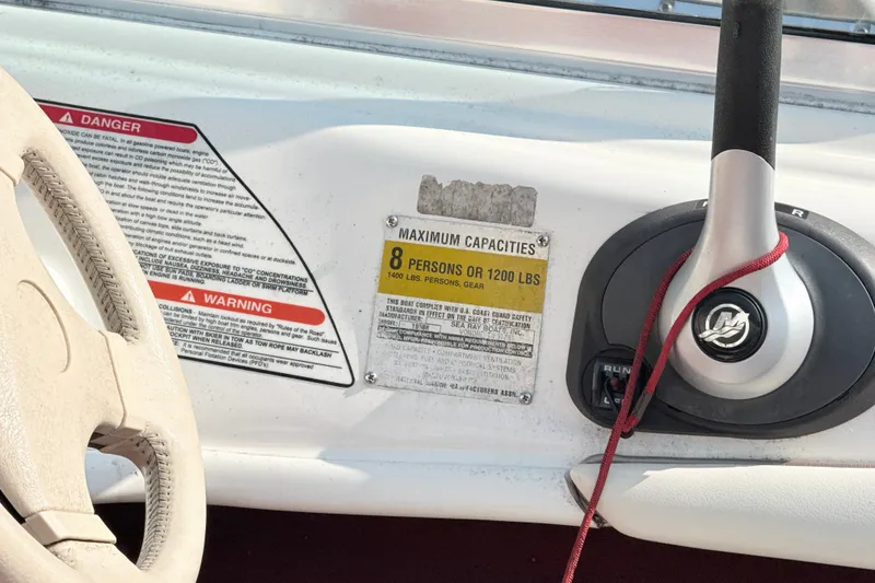 Slide: The Image of 1995 Searay 195 boat dashboard with capacity warning labels and steering wheel. - 6