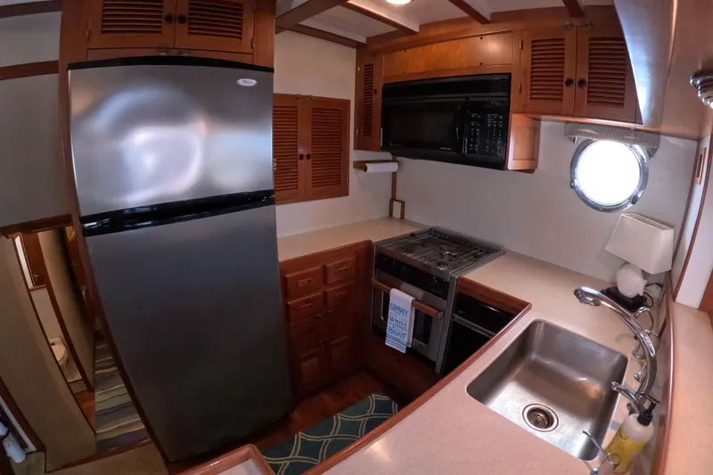 Slide: The Image of 1999 Kadey-Krogen 48 North Sea yacht kitchen with stainless steel appliances and wooden cabinetry. - 15