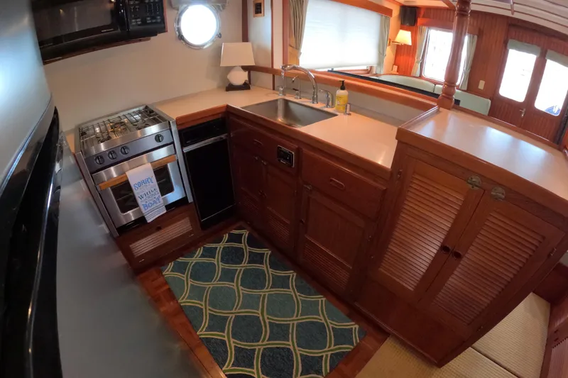 Slide: The Image of 1999 Kadey-Krogen 48 North Sea yacht kitchen with stove, sink, and wooden cabinetry. - 17