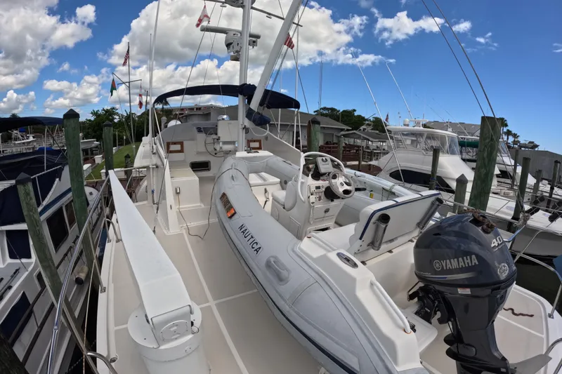 Slide: The Image of 1999 Kadey-Krogen 48 North Sea yacht docked, featuring a Yamaha motor and inflatable boat. - 62