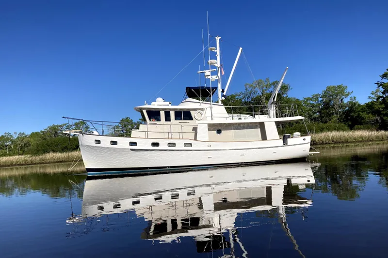 The Image of 1999 Kadey-Krogen 48 North Sea yacht reflecting on calm water under clear blue sky. - 0