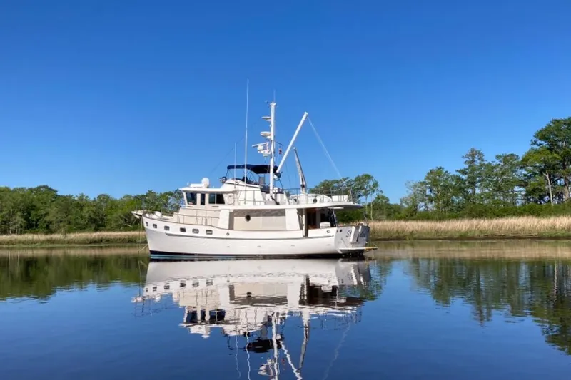 Slide: The Image of Kadey-Krogen 48 North Sea yacht from 1999 on calm water, surrounded by trees. - 2