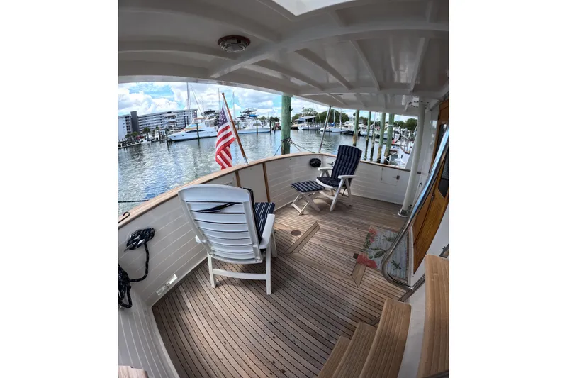 Slide: The Image of 1999 Kadey-Krogen 48 North Sea yacht deck with chairs, overlooking marina and American flag. - 48