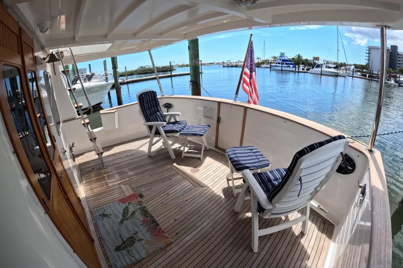 Slide: The Image of 1999 Kadey-Krogen 48 North Sea yacht deck with chairs, American flag, and marina view. - 47