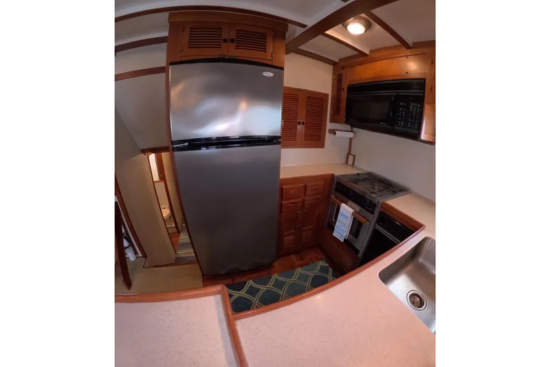 Slide: The Image of 1999 Kadey-Krogen 48 North Sea yacht kitchen with stainless steel appliances and wooden cabinetry. - 14