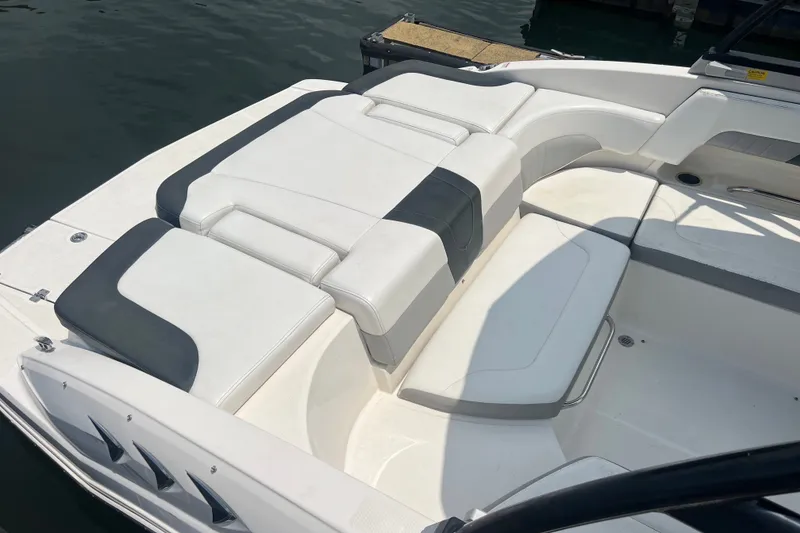 Slide: The Image of 2020 Chaparral 23 SSi boat interior with white and gray seating, docked on water. - 4
