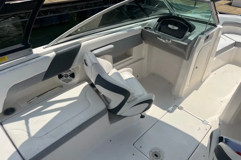 Slide: The Image of 2020 Chaparral 23 SSi boat interior with seating and dashboard, docked by the water. - 5