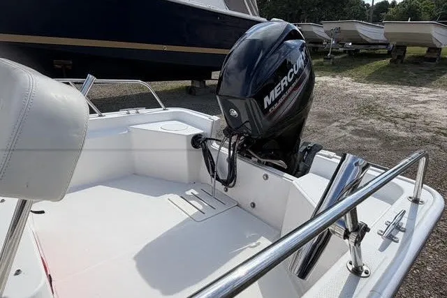Slide: The Image of 2019 Boston Whaler 150 Montauk boat with Mercury outboard motor, docked outdoors. - 6