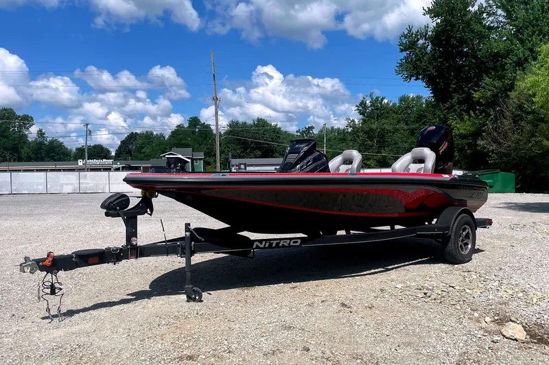 Slide: The Image of A 2024 Nitro Z18 boat on a trailer in a gravel lot, surrounded by trees. - 3