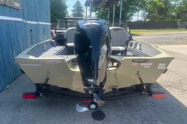 Slide: The Image of 2027 Tracker Pro Guide V-16 WT boat, rear view with outboard motor, parked outdoors. - 3