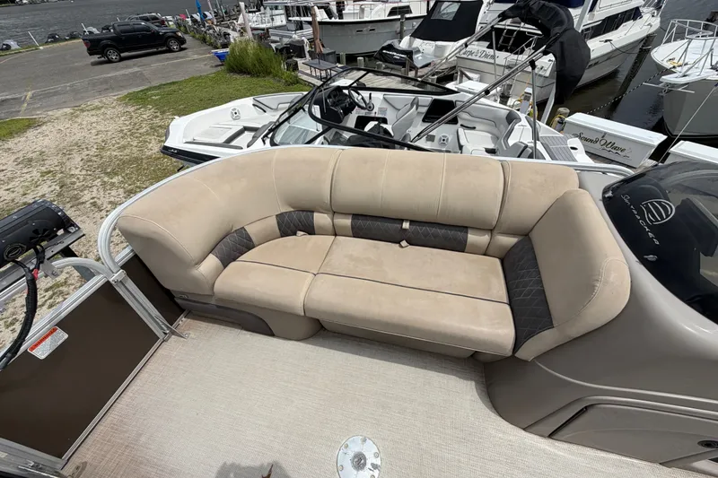 Slide: The Image of 2020 Sun Tracker Party Barge 22 DLX with beige seating, docked near other boats. - 4