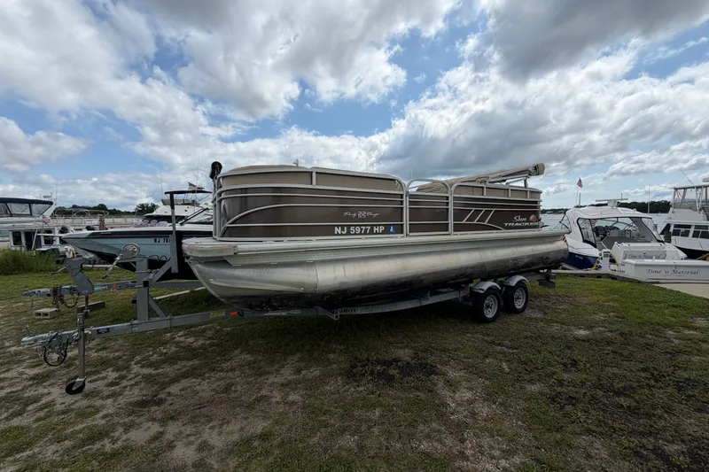 The Image of 2020 Sun Tracker Party Barge 22 DLX pontoon boat on trailer under cloudy sky. - 0