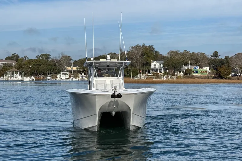 Slide: The Image of 2021 SeaHunter 41 CTS boat cruising on calm waters near a coastal town. - 7