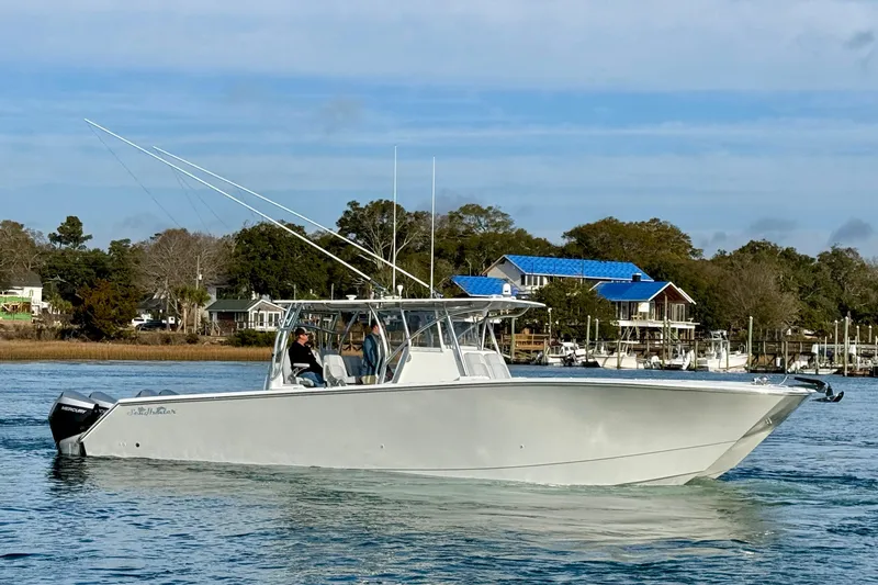 The Image of 2021 SeaHunter 41 CTS boat cruising on a calm waterway near a coastal town. - 0