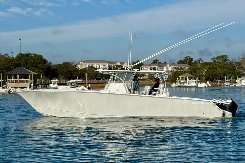 Slide: The Image of 2021 SeaHunter 41 CTS boat on calm water, with scenic marina background. - 2