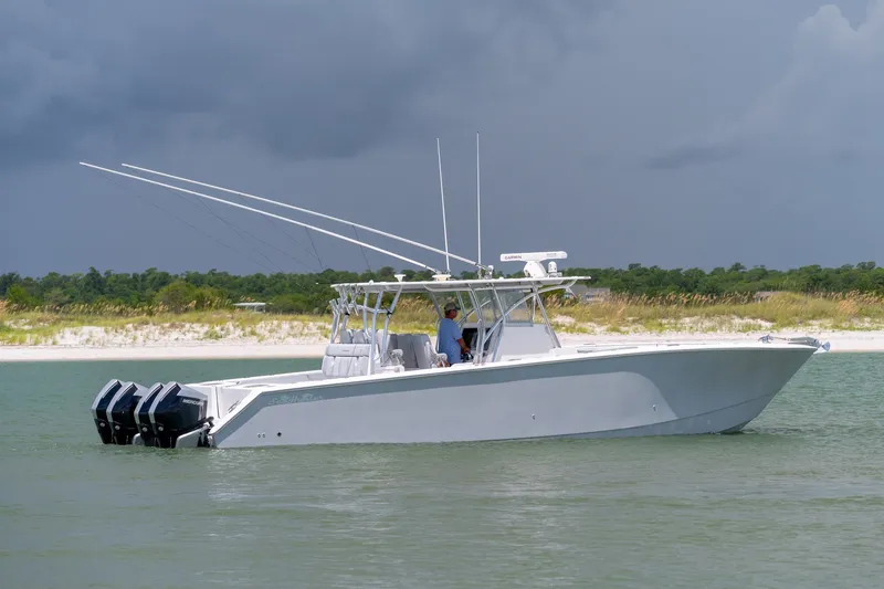 Slide: The Image of 2021 SeaHunter 41 CTS boat on calm water near a sandy shoreline under cloudy skies. - 23