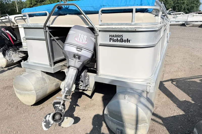 Slide: The Image of 1991 Harris FloteBote 240 pontoon boat with outboard motor, parked on gravel. - 7