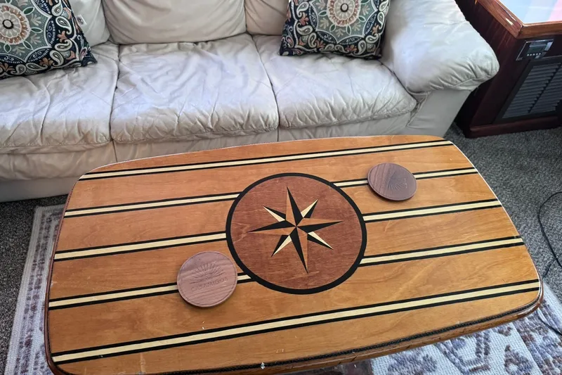 Slide: The Image of An elegant wooden table with a compass rose design, surrounded by beige sofas and decorative pillows. - 25