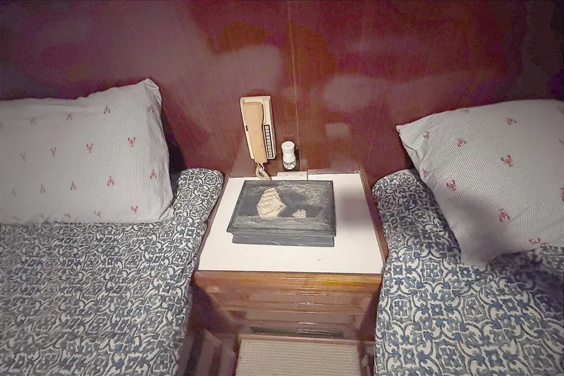 Slide: The Image of Interior of 1981 Hatteras 43 Convertible with twin beds and nautical-themed bedding. - 44